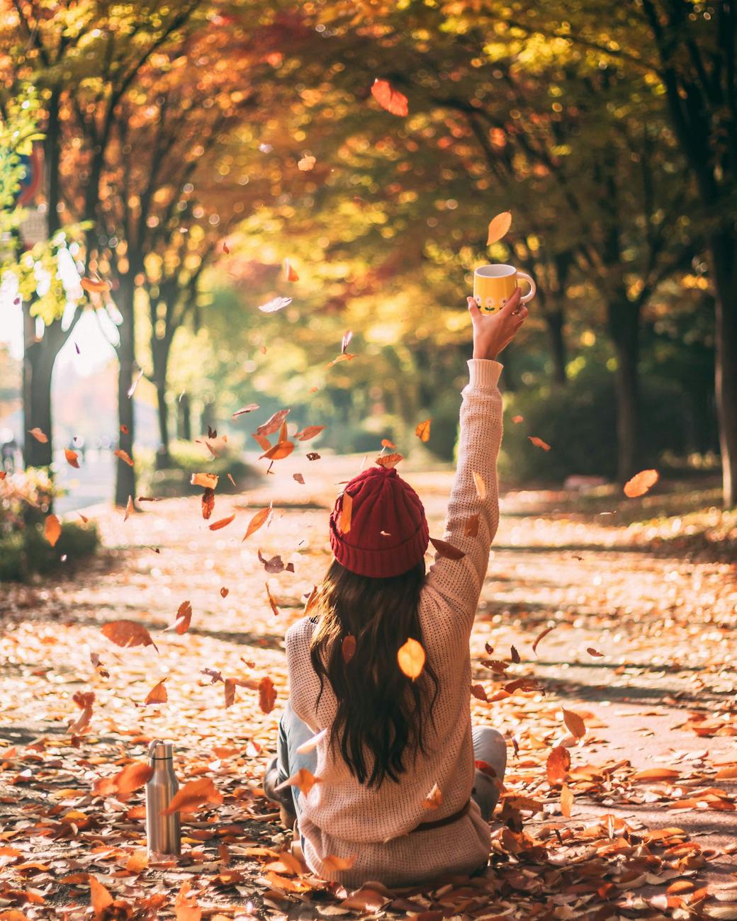 woman sitting on dry leaves on ground