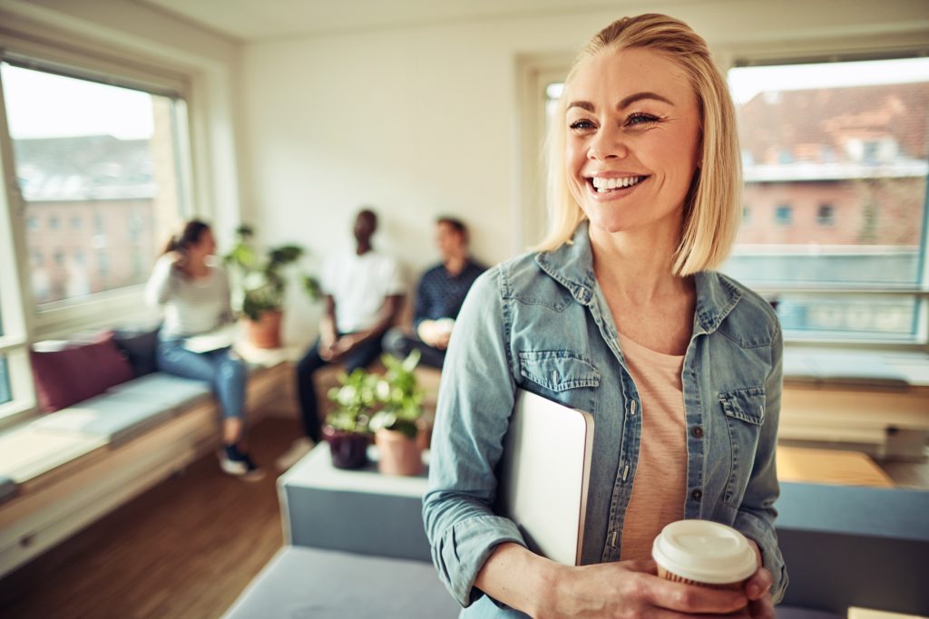 Silke Mekat Effizient arbeiten, gelassen leben: Trainerin & Coach für Zeitmanagement, Selbstorganisation & Stressprävention – für ein souveränes Berufs- und Privatleben. foto von AdobeStock_205532183 laughing young businesswoman drinking coffee during her office b